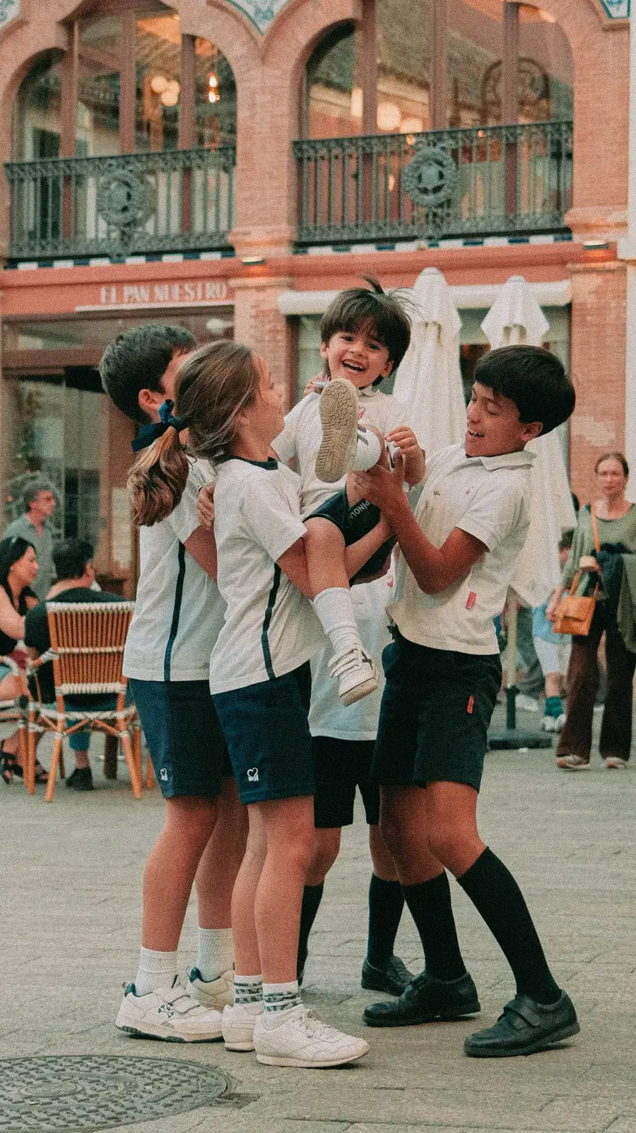 Un grup d'alumnes amb uniforme jugant a la plaça davant de l'escola