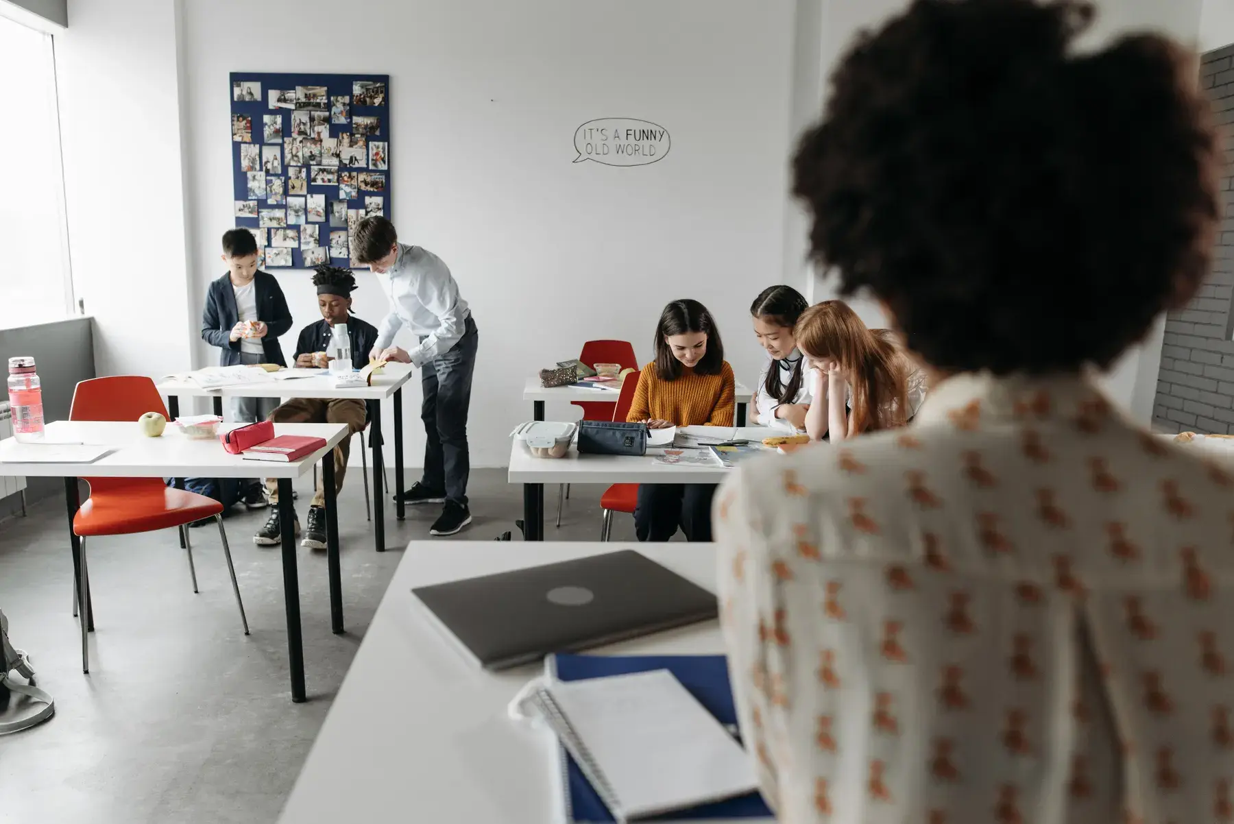 Una aula amb alumnes treballant en grups mentre la mestra els observa